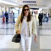Miranda Kerr, souriante à l'aéroport de Los Angeles, porte une petite veste blanche Chanel sur un top blanc, un jean blanc Mango, un sac Valentino et des mocassins léopard Prada. Le 6 novembre 2013.