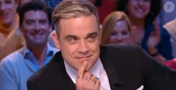 Antoine de Caunes montre ses fesses au chanteur Robbie Williams dans "Le grand journal de Canal +", mardi 26 novembre 2013.