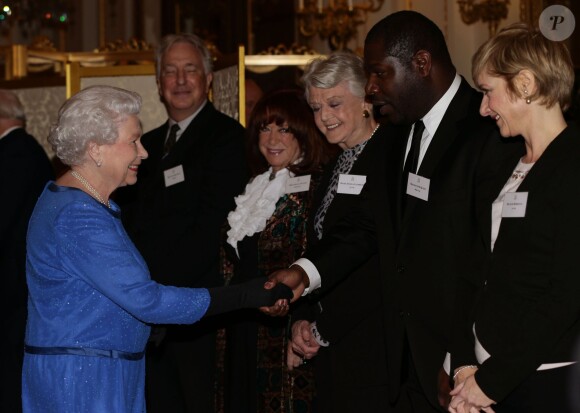 La reine Elizabeth II serre la main du réalisateur de 12 Years a Slave Steve McQueen lors de la réception organisée le 17 février 2014 à Buckingham Palace pour célébrer les soixante ans du patronage de la Royal Academy of Dramatic Art par la reine Elizabeth II.