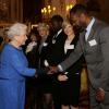 Elizabeth II saluant Lenny Henry lors de la réception organisée le 17 février 2014 à Buckingham Palace pour célébrer les soixante ans du patronage de la Royal Academy of Dramatic Art par la reine Elizabeth II.