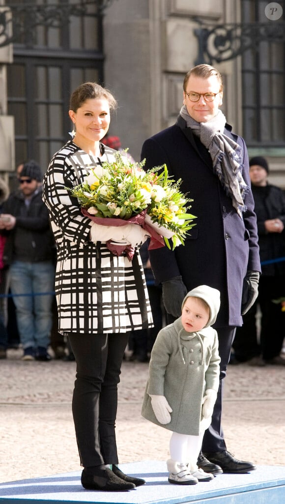 La princesse Victoria, les bras chargés de fleurs, le prince Daniel et leur fille la princesse Estelle de Suède lors de la cérémonie organisée à l'occasion du jour de la Sainte Victoria dans la cour intérieur du palais royal à Stockholm, le 12 mars 2014.