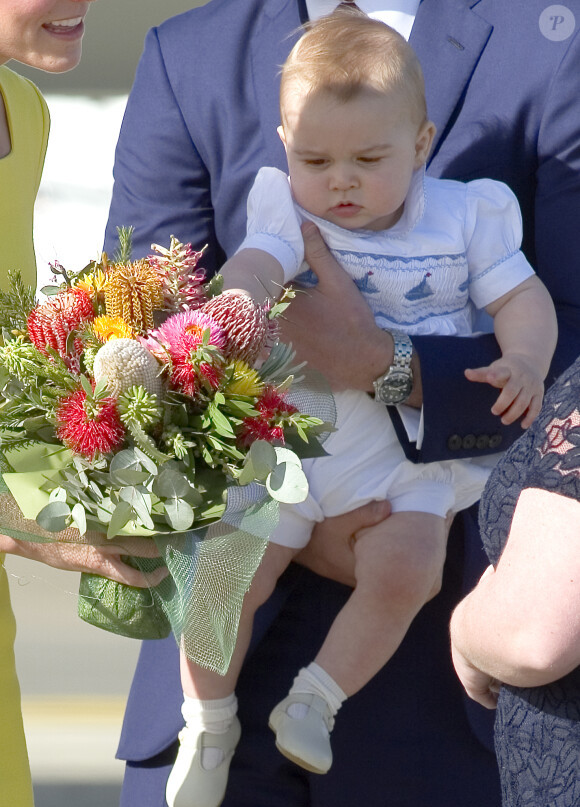 Le prince George de Cambridge, fils du prince William et de Kate Middleton, visiblement attiré par un bouquet de fleurs multicolore lors de leur arrivée à l'aéroport de Sydney le 16 avril 2014