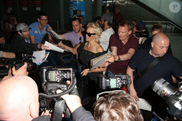 Pamela Anderson, attendue par de nombreux fans à qui elle a signé des autographes, arrive avec son mari Rick Salomon à l'aéroport de Nice pour le festival de Cannes, le 13 mai 2014.