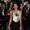 Kendall Jenner, habillée d'une robe (collection croisière 2014) et d'une pochette Chanel, de bijoux Chopard et de sandales Stuart Weitzman, monte les marches pour la cérémonie d'ouverture du 67e Festival de Cannes et la projection du film Grâce de Monaco. Cannes, le 14 mai 2014.