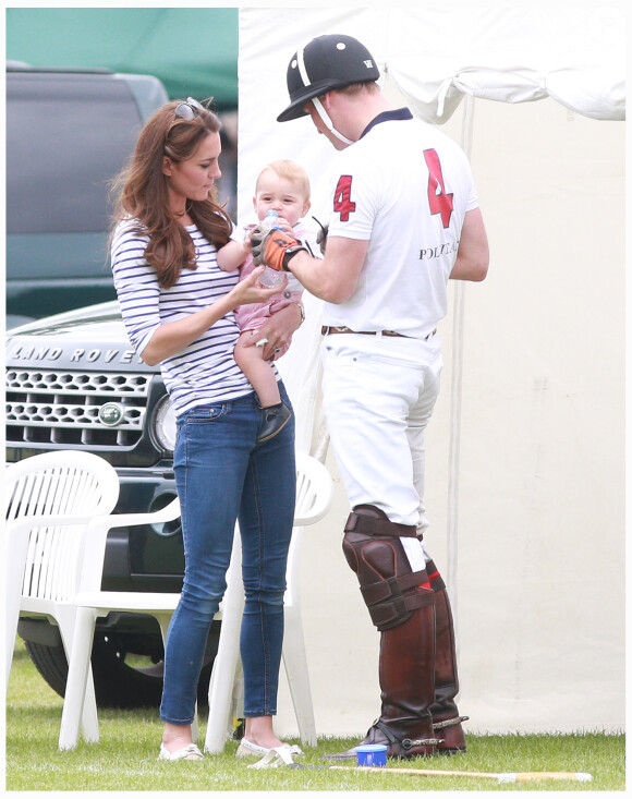 Kate Middleton et le prince George de Cambridge, qui se désaltère à la bouteille de papa, avec le prince William lors du Jerudong Trophy le 15 juin 2014 au Cirencester Park, près de Londres.