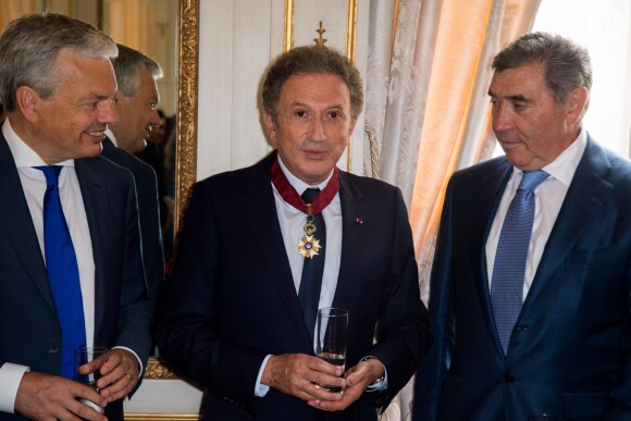 Didier Reynders, Michel Drucker et Eddy Merckx, à l'occasion de la cérémonie de remise des insignes de commandeur de l'Ordre de la Couronne à Michel Drucker au palais d'Egmont à Bruxelles le 27 juin 2014. 