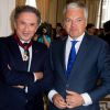 Didier Reynders (Vice-Premier Ministre et Ministre des Affaires étrangères) et Michel Drucker, à l'occasion de la cérémonie de remise des insignes de commandeur de l'Ordre de la Couronne à Michel Drucker au palais d'Egmont à Bruxelles le 27 juin 2014.