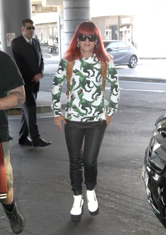 Lily Allen arrive à l'aéroport de Sydney, habillée d'un pull Au Jour le Jour, d'un sac à dos MCM, d'un jean noir et de chaussures blanches. Le 27 juillet 2014.