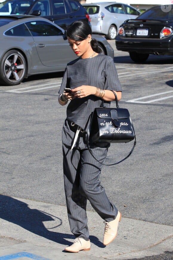 Rihanna, entièrement habillée en Alexander Wang (t-shirt en pantalon rayés de la pré-collection automne 2014, chaussures de la collection croisière 2013) et portant un sac Delvaux, quitte le restaurant Le Petit Four à West Hollywood. Le 12 août 2014.