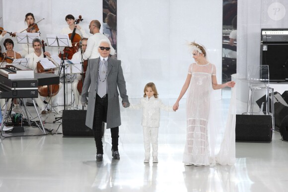 Karl Lagerfeld salue à la fin de son défilé Chanel aux côté de son filleul Hudson et de Cara Delevingne, au Grand Palais à Paris, le 21 janiver 2014.
