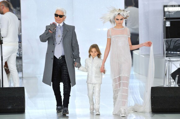 Karl Lagerfeld salue à la fin de son défilé Chanel aux côté de son filleul Hudson et de Cara Delevingne, au Grand Palais à Paris, le 21 janiver 2014.