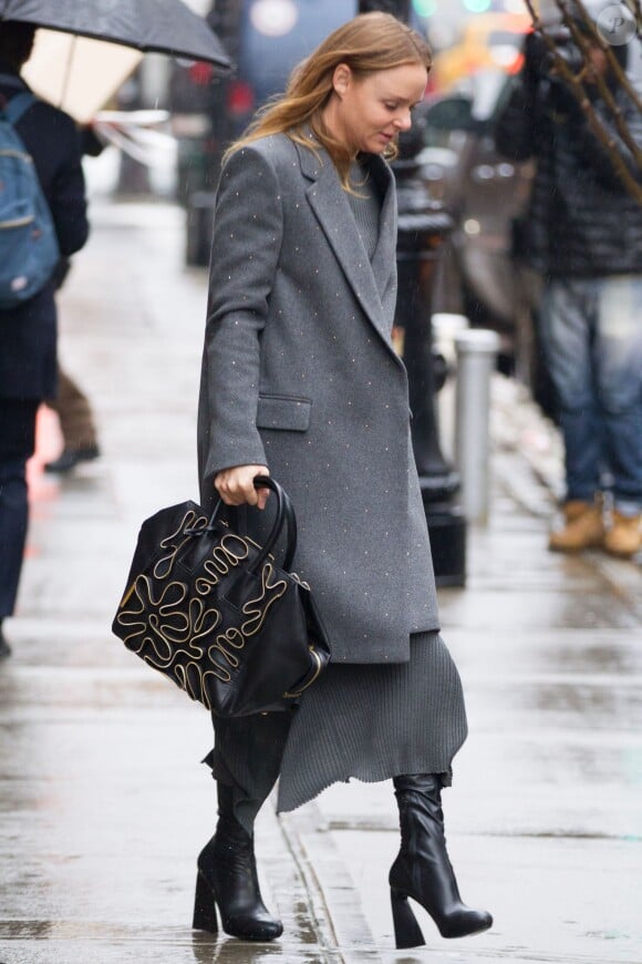 Stella McCartney quitte un hôtel à New York, tout de gris vêtue avec un manteau oversize gris cloutée, un top et une jupe asymétriques gris, un sac noir (modèle Cavendish) Stella McCartney et des bottines. Le 12 janvier 2014.