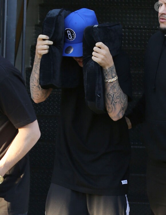 Justin Bieber se cache des photographes à la sortie d'un salon de coiffure à West Hollywood, le 27 janvier 2015 