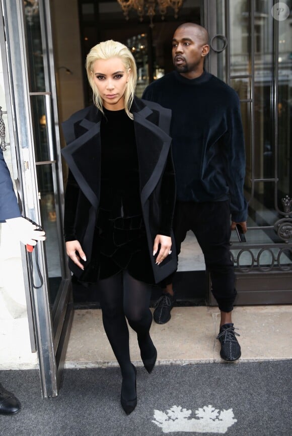 Kim Kardashian et Kanye West sortent de l'hôtel Royal Monceau à Paris. Kim porte un manteau à revers en satin, un top et une jupe en velours Balmain, des collants et des souliers en satin et mesh Gianvito Rossi. Le 5 mars 2015.