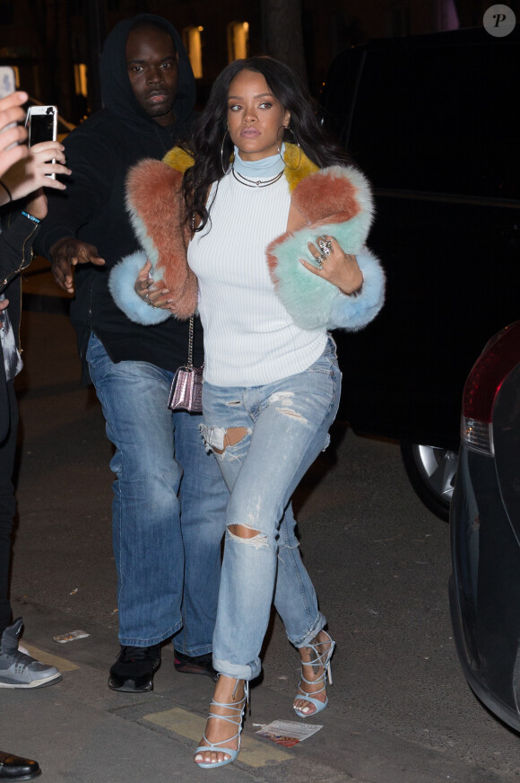 Rihanna passe aux boutiques L'Eclaireur et Market Montaigne à Paris, habillée d'une veste en fourrure MaryMe-JimmyPaul, un débardeur blanc à col roulé, un jean craqué et des sandales Dsquared&sup2; (pré-collection automne 2015). Le 7 mars 2015.