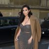 Kim Kardashian arrive au restaurant Ferdi, habillée d'un manteau Céline (collection automne-hiver 2013-2014), d'un ensemble top bustier et jupe transparent, et de sandales Alexander Wang (modèle Antonia). Paris, le 15 avril 2015.