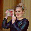 La chanteuse Adele (Adele Adkins) pose avec sa medaille (MBE), apres avoir ete decoree par le prince Charles, prince de Galles pour ses talents musicaux lors d'une ceremonie au palais de Buckingham a Londres, le 19 decembre 19, 2013.19/12/2013 - Londres