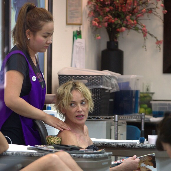 Sharon Stone lit le magazine "OK!" et se fait masser la tête pendant sa manucure/pédicure à Beverly Hills, le 20 juillet 2015. 