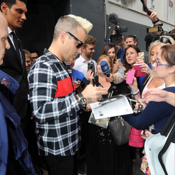 Robbie Williams et sa femme Ayda Field sortent de la vente aux enchères caritative des objets du chanteur au profit du Donna Louise Children's Hospice chez Bonhams à Londres, le 15 juillet 2015.