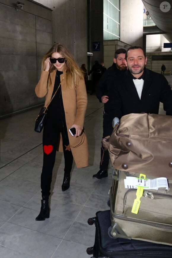 Arrivée de Gigi Hadid à l'aéroport Roissy CDG à Roissy, toute de noir vêtue à l'exception d'un manteau beige, avec un sac Saint Laurent et des bottines Stuart Weitzman (modèle Zepher). Paris, le 19 janvier 2016.