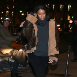 Rihanna arrive au restaurant Caviar Kaspia à Paris, habillée d'un manteau (collection automne-hiver 2015) et d'un pull à col roulé Vetements, d'un legging et de bottes Chanel. Le 18 janvier 2016.
