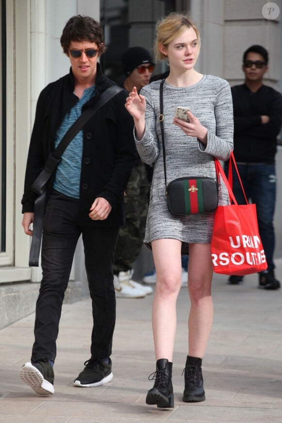 Elle Fanning quitte un magasin Urban Outfitters à Los Angeles, habillée d'une petite robe grise Michael Lauren (modèle "Harvest") et portant un sac Gucci et des chaussures Timberland. Le 16 janvier 2016.
