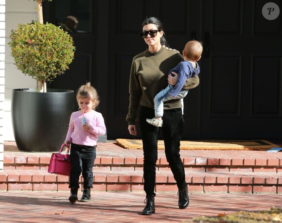 Kourtney Kardashian surprise avec ses enfants Penelope (qui porte un petit sac à main Hermès rose) et Reign à Beverly Hills, porte un pull olive Balmain, un pantalon en velours noir et des bottines Saint Laurent (modèle Lolita). Le 21 janvier 2016.