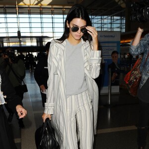 Kendall Jenner à l'aéroport LAX, porte un trench-coat, un top gris et un pantalon Sally LaPointe (pré-collection automne 2016), un sac Givenchy (modèle Nightingale) et des baskets Céline. Los Angeles, le 20 janvier 2016.