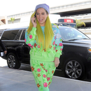 Kesha, les cheveux jaune, arrive à l'aéroport de LAX pour prendre l’avion. La coque de téléphone de Kesha est une poupée en 3D! Le 4 juillet 2015