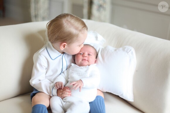 Le prince George avec sa soeur la princesse Charlotte de Cambridge sur les genoux, en mai 2015, après sa naissance, photographiés par leur maman Kate Middleton.
