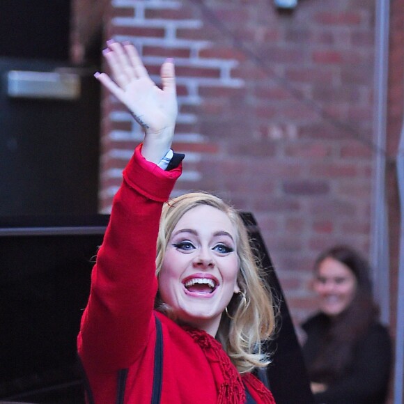 La chanteuse Adele salue ses fans habillée d'un manteau rouge au Joe's pub de New York le 20 novembre 2015