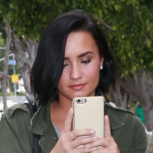 Demi Lovato à la sortie d'un immeuble accompagnée de son garde du corps à West Hollywood. Demi s'amuse à prendre les photographes en photo avec son Iphone. Le 18 mai 2016