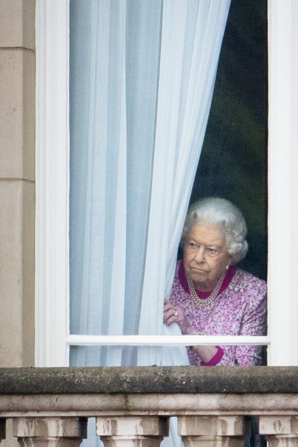 La reine Elizabeth II regardant par une fenêtre du Palais de Buckingham le 12 juin 2016 le Mall lors du Patron's Lunch, le pique-nique géant sur le Mall en l'honneur de son 90e anniversaire.