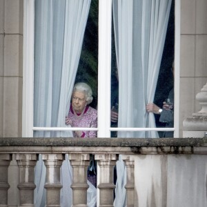 La reine Elizabeth II regardant par une fenêtre du Palais de Buckingham le 12 juin 2016 le Mall lors du Patron's Lunch, le pique-nique géant sur le Mall en l'honneur de son 90e anniversaire.