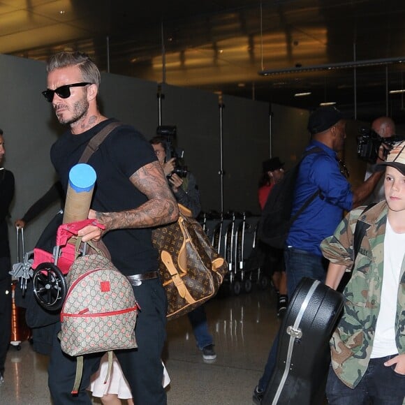 La famille Beckham arrive à l'aéroport de LAX à Los Angeles. David Beckham tient la main de sa fille Harper, Brooklyn marche aux côtés de sa mère Victoria, le petit Cruz porte tout seul sa guitare et Roméo porte son skateboard. Le 29 août 2016.
