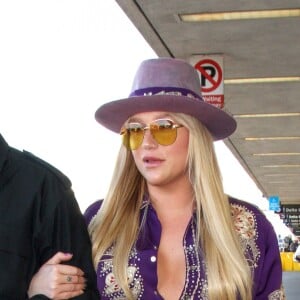La chanteuse Kesha arrive, bras dessus bras dessous avec son garde du corps, à l'aéroport LAX de Los Angeles pour prendre un avion, le jour de la Saint-Valentin. Le 14 février 2017
