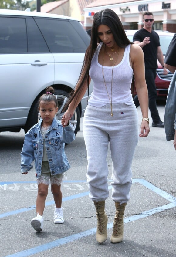 Kim Kardashian, habillée d'un débardeur blanc, d'un jogging Champion et de bottines YEEZY (collection Season 4), sort avec sa fille North West à Los Angeles le 10 mars 2017.