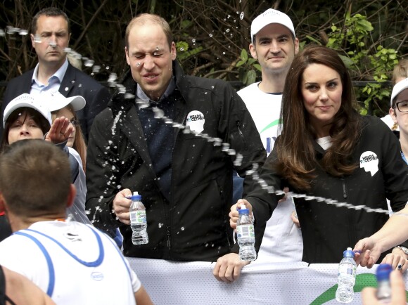 Un concurrent balance une gerbe d'eau en direction du prince William, de Kate Middleton, qui regarde d'un oeil désapprobateur, et du prince Harry lors du marathon de Londres, le 23 avril 2017.