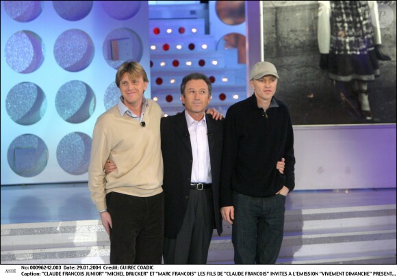 <b></b><span>Michel Drucker au côté des fils de Claude François, Claude François Junior et Marc François, sur le plateau de l'émission Vivement Dimanche en janvier 2004</span>
