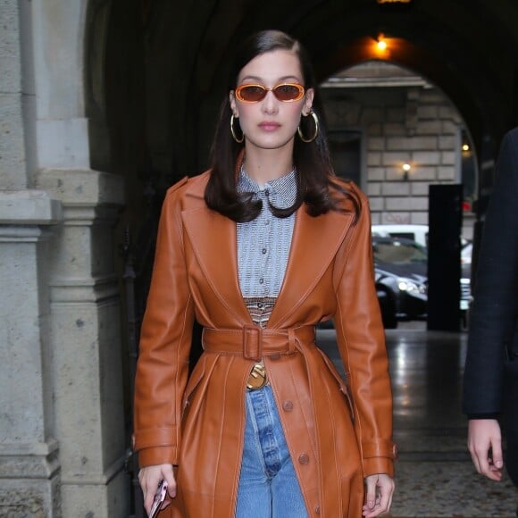 Bella Hadid porte des lunettes Le Specs (modèle "Outta Love"), un trench-coat en cuir et un jean RE/DONE à Milan. Le 22 février 2018.