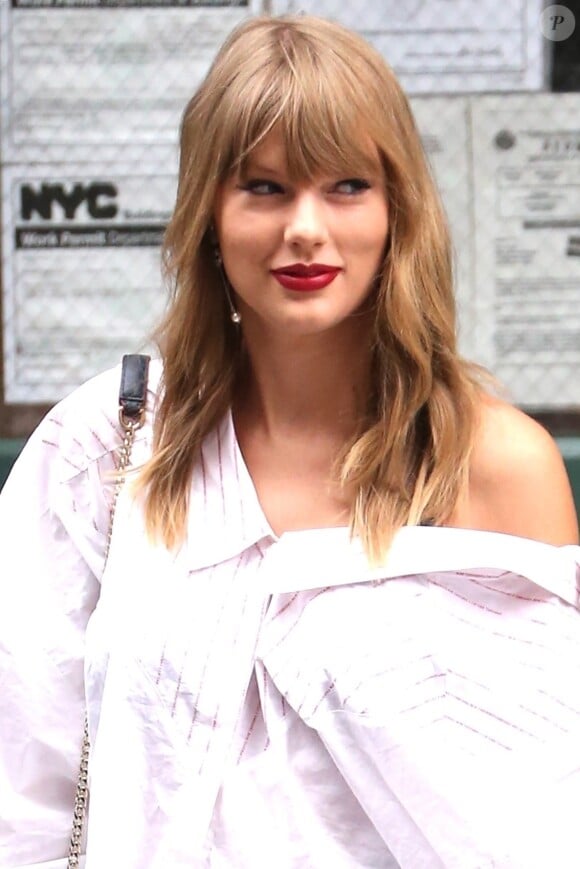 Taylor Swift quitte son appartement à New York. La chanteuse porte un mini short en jean, une blouse blanche et des bottines noires à talons, le 22 juillet 2018.