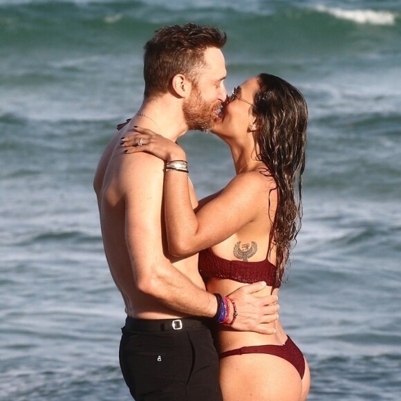 David Guetta et sa compagne Jessica Ledon, qui porte un diamant à l'annulaire gauche, passent du bon temps sur la plage en compagnie de leur petit chien. Miami, le 23 novembre 2018.