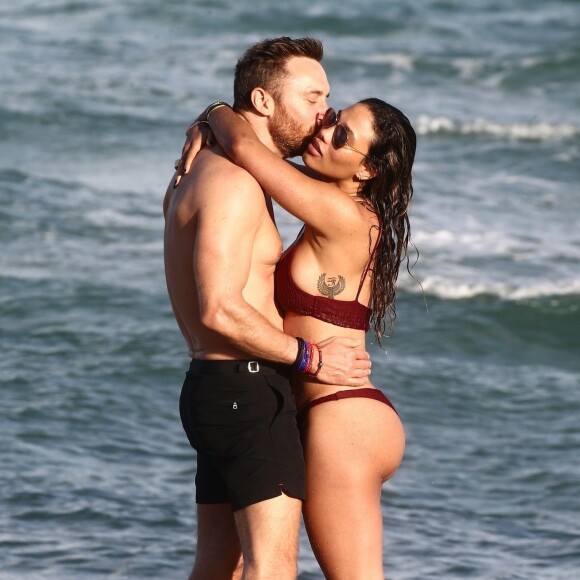 David Guetta et sa compagne Jessica Ledon, qui porte un diamant à l'annulaire gauche, passent du bon temps sur la plage en compagnie de leur petit chien. Miami, le 23 novembre 2018.