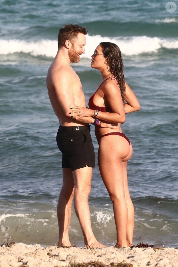 David Guetta et sa compagne Jessica Ledon, qui porte un diamant à l'annulaire gauche, passent du bon temps sur la plage en compagnie de leur petit chien. Miami, le 23 novembre 2018.