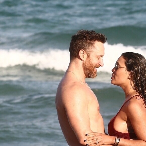 David Guetta et sa compagne Jessica Ledon, qui porte un diamant à l'annulaire gauche, passent du bon temps sur la plage en compagnie de leur petit chien. Miami, le 23 novembre 2018.