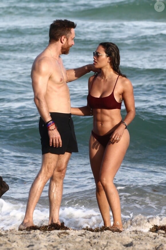 David Guetta et sa compagne Jessica Ledon, qui porte un diamant à l'annulaire gauche, passent du bon temps sur la plage en compagnie de leur petit chien. Miami, le 23 novembre 2018.