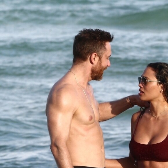 David Guetta et sa compagne Jessica Ledon, qui porte un diamant à l'annulaire gauche, passent du bon temps sur la plage en compagnie de leur petit chien. Miami, le 23 novembre 2018.