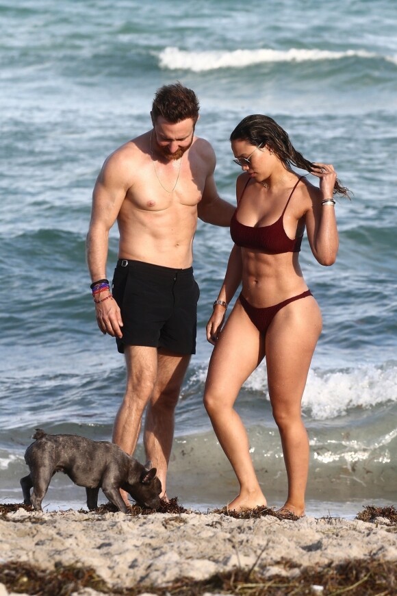 David Guetta et sa compagne Jessica Ledon, qui porte un diamant à l'annulaire gauche, passent du bon temps sur la plage en compagnie de leur petit chien. Miami, le 23 novembre 2018.