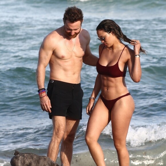 David Guetta et sa compagne Jessica Ledon, qui porte un diamant à l'annulaire gauche, passent du bon temps sur la plage en compagnie de leur petit chien. Miami, le 23 novembre 2018.