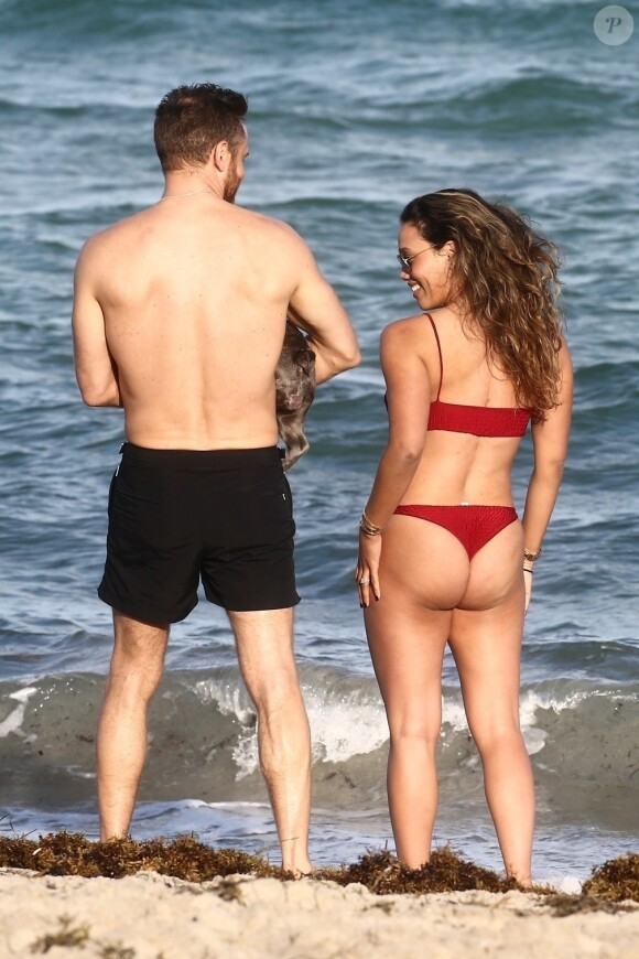 David Guetta et sa compagne Jessica Ledon, qui porte un diamant à l'annulaire gauche, passent du bon temps sur la plage en compagnie de leur petit chien. Miami, le 23 novembre 2018.